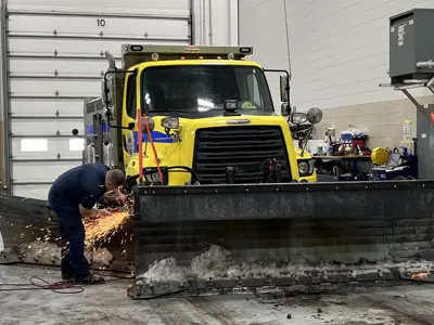 Fleet mechanic working on highway operations plow