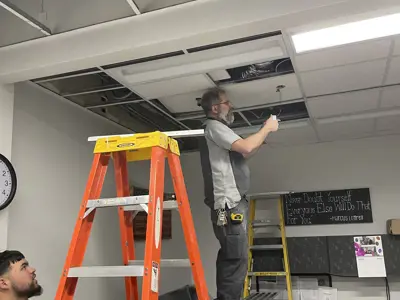 Facilities worker on a ladder