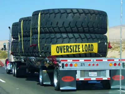 Semi truck hauling large tires with oversize load sign